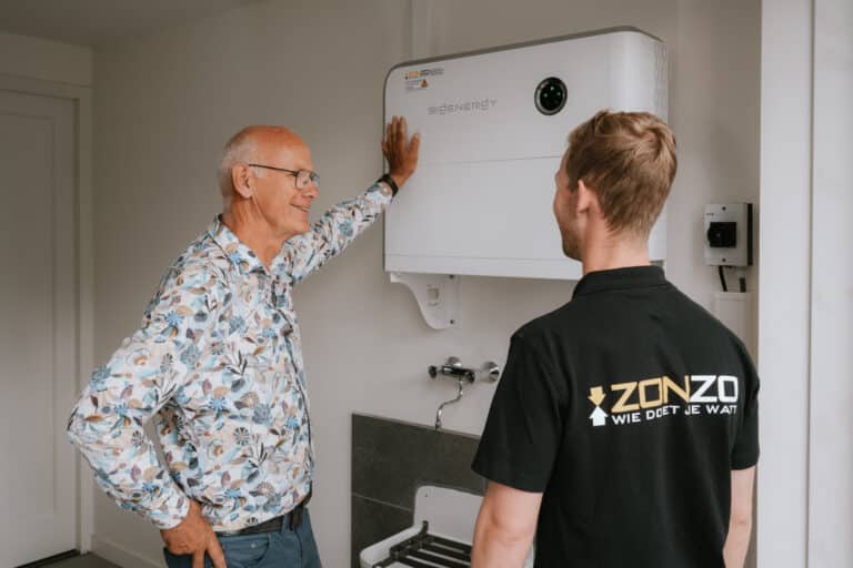 Zonzo klant krijgt uitleg van verkoper over de werking van de geïnstalleerde thuisbatterij en hybride omvormer